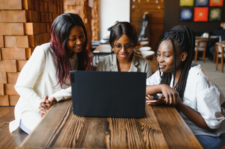 Three African American girls (students) sitting at the table in cafe studying